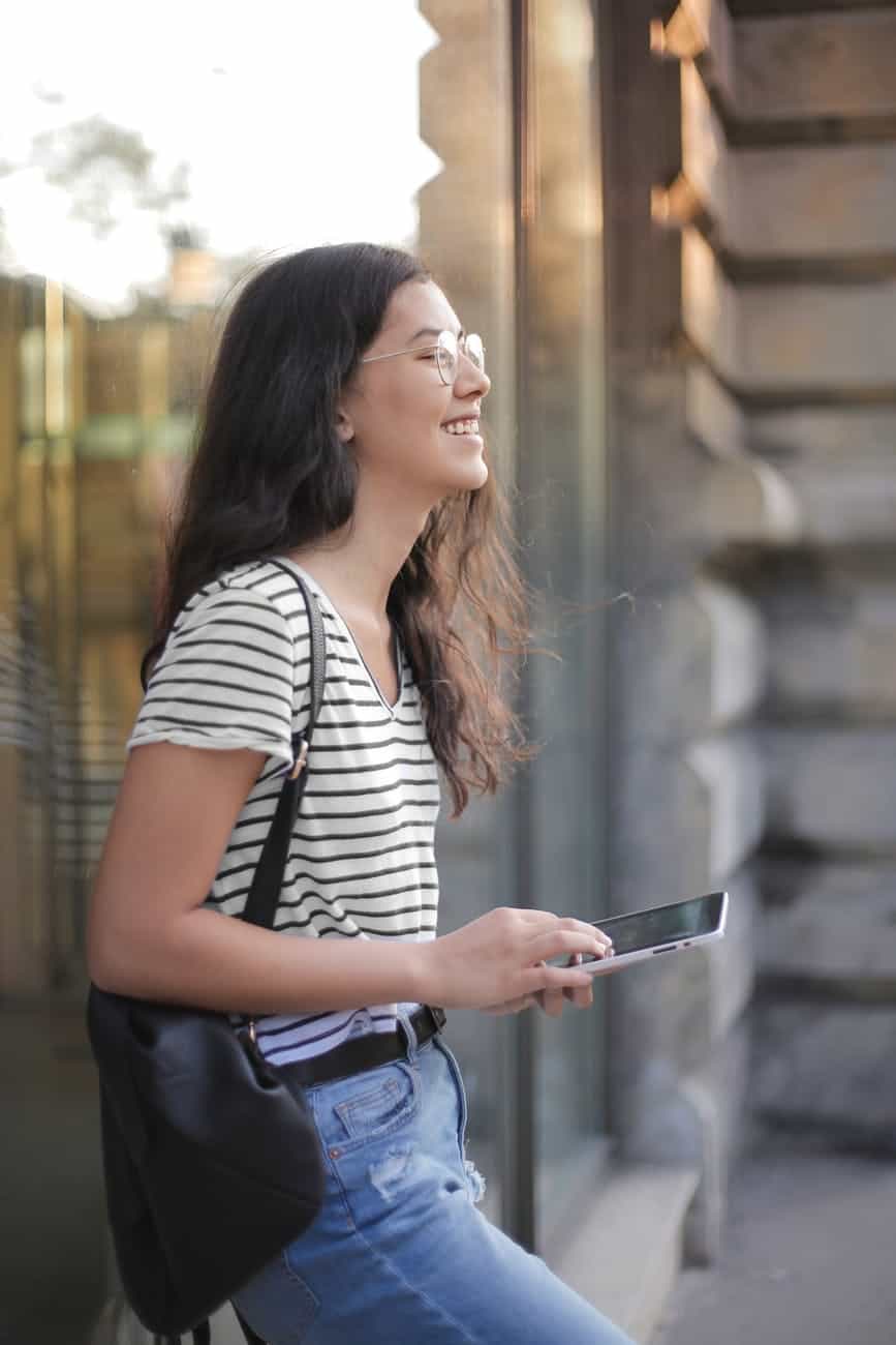 cheerful young woman using smartphone in street