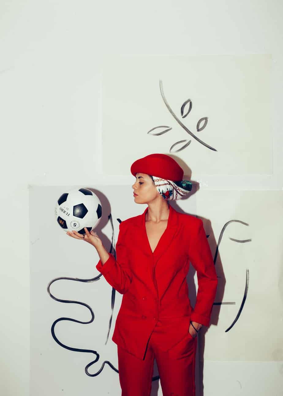woman in red blazer holding white and black soccer ball