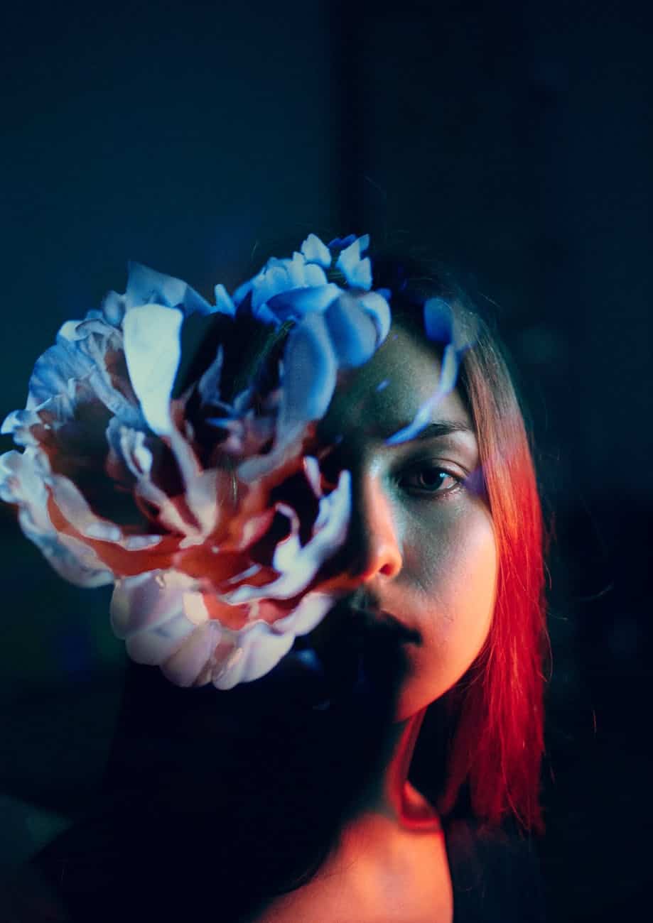 calm young woman with flower in dark room